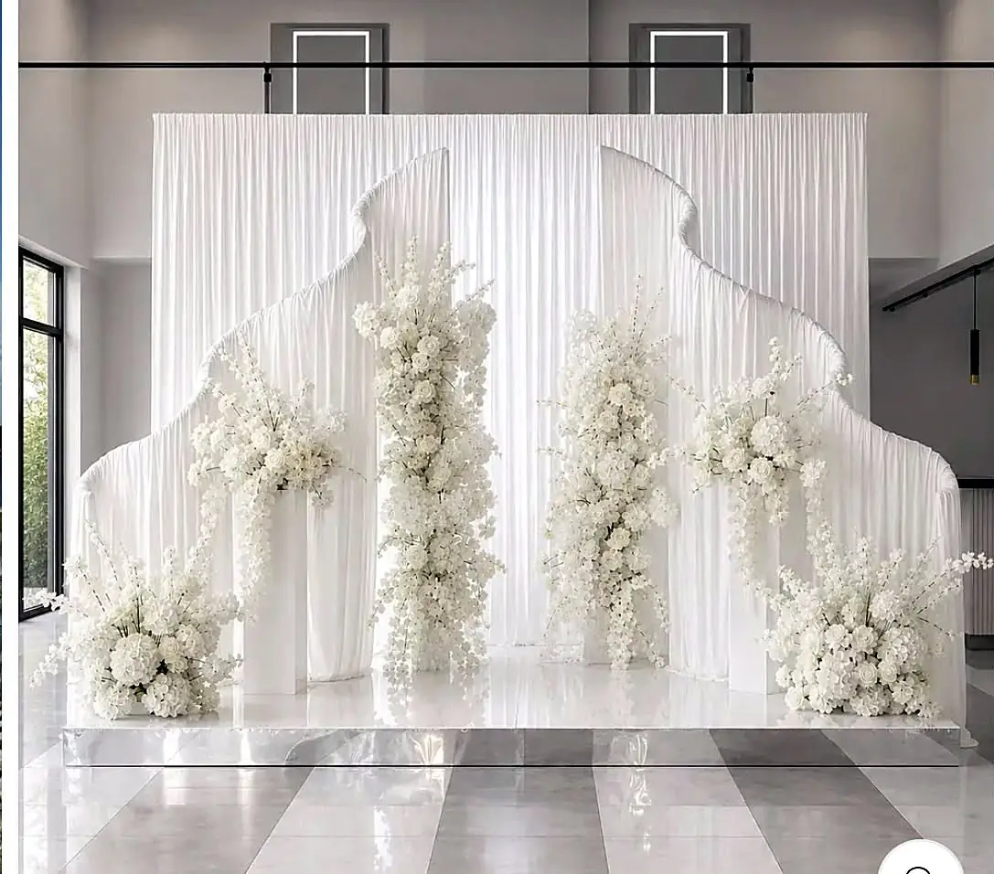 All-white draped backdrop with cascading white floral installations on a mirrored platform by Bsquare Events