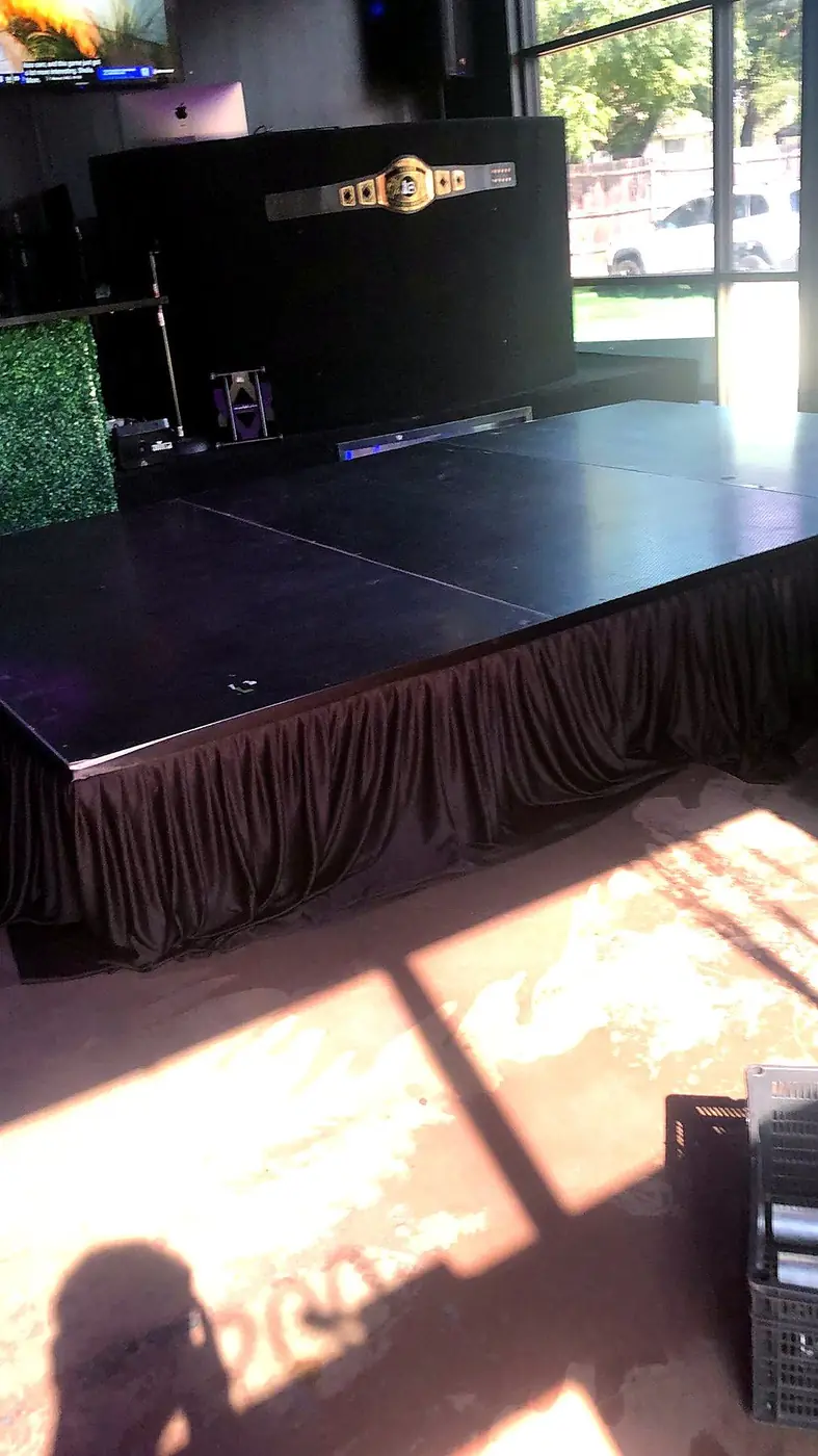 Black modular stage platform with dark skirting installed in a venue by Bsquare Events
